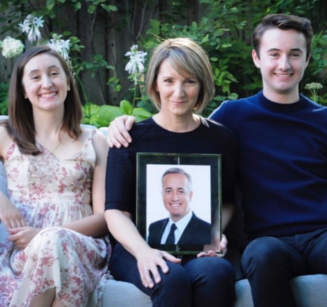 Isobel, Janet, Sam Fanaki. A portrait of Adam Fanaki who passed away in 2020 of glioblastoma is held by Janet. 